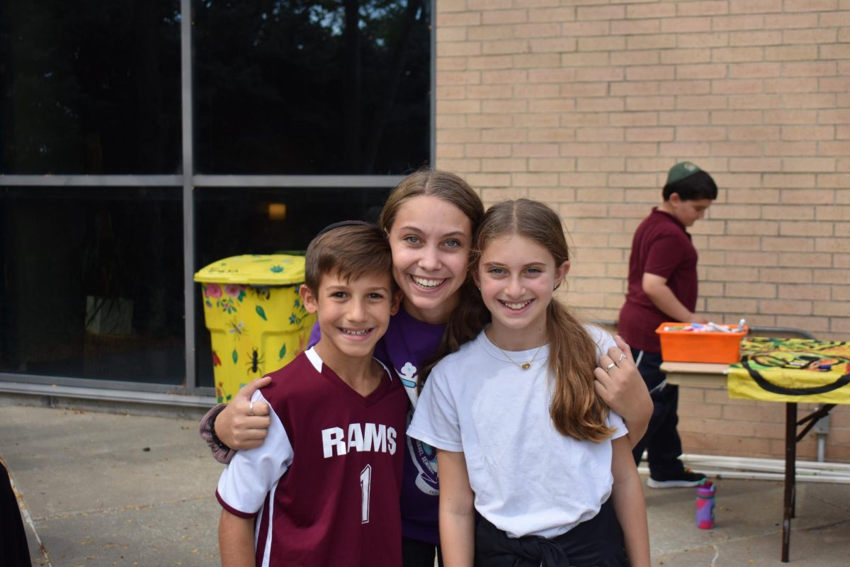Senior Emma Rosenthal posing with two fifth graders during the Sukkot family program.