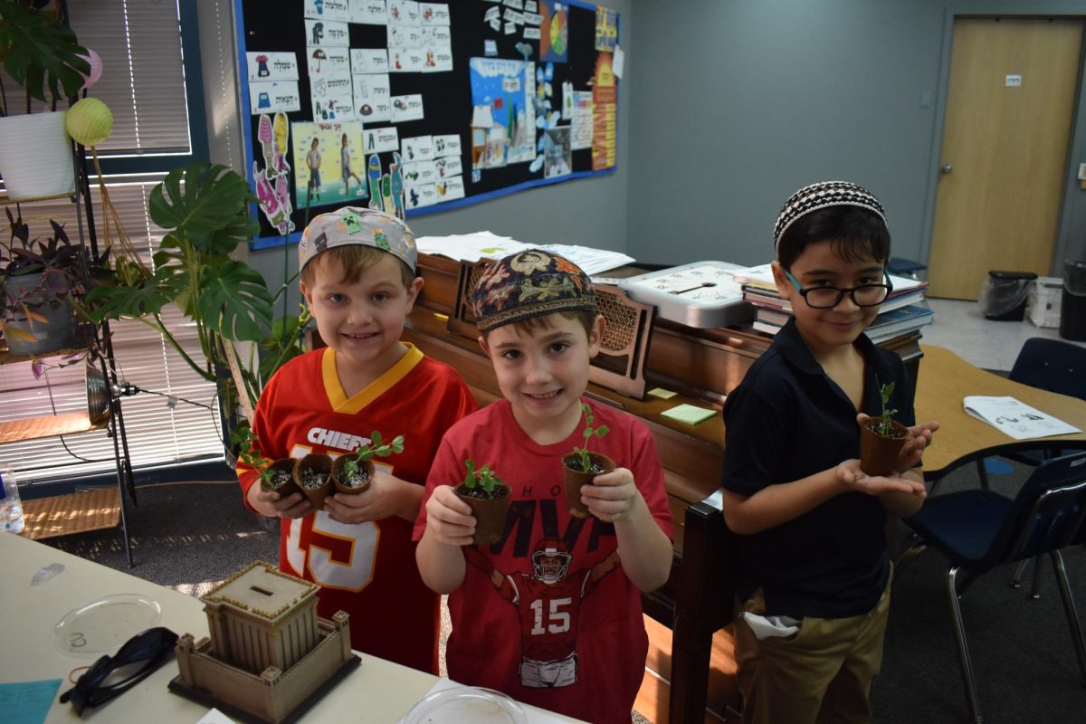 Three first-graders, (left to right) Caleb, Max, and Liam learn about growing trees. When I went to visit and take some pictures for this article, I saw this class reading to their trees which according to Max Lerner, promotes growth and is good for the trees. Photo by Teddy Zitron.